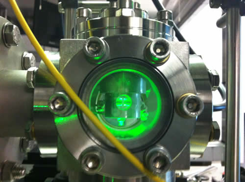 An ion trap levitating a 10um diameter glass sphere, illuminated with a green laser. The sphere looks bigger than it actually is because of the light scattering off it